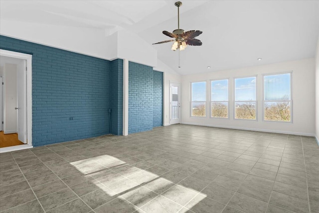 interior space with a ceiling fan, tile patterned flooring, vaulted ceiling, and brick wall