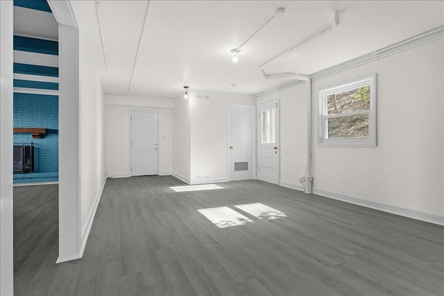 unfurnished room featuring a fireplace, wood finished floors, visible vents, and baseboards