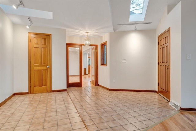 3615 Dogwood Ln SW, Roanoke, VA 24015 - unfurnished room featuring rail lighting, a skylight, a chandelier, light tile patterned floors, and baseboards