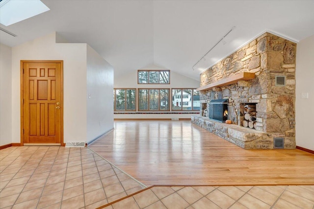 3615 Dogwood Ln SW, Roanoke, VA 24015 - unfurnished living room with vaulted ceiling, wood finished floors, a skylight, track lighting, and a stone fireplace