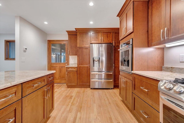 3615 Dogwood Ln SW, Roanoke, VA 24015 - kitchen with appliances with stainless steel finishes, brown cabinets, light wood-style flooring, light stone countertops, and recessed lighting
