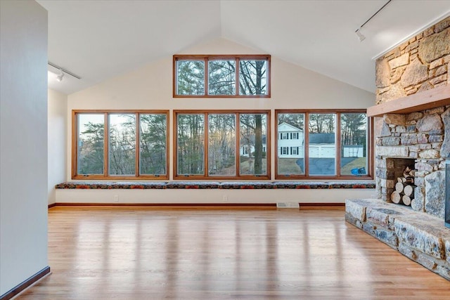 3615 Dogwood Ln SW, Roanoke, VA 24015 - unfurnished living room with track lighting, wood finished floors, high vaulted ceiling, and a stone fireplace