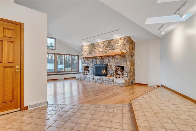 3615 Dogwood Ln SW, Roanoke, VA 24015 - unfurnished living room with track lighting, lofted ceiling, a skylight, a fireplace, and baseboards