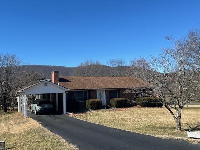 ranch-style house with a carport, a mountain view, and a front yard