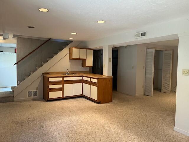 kitchen featuring white cabinetry, sink, and light carpet