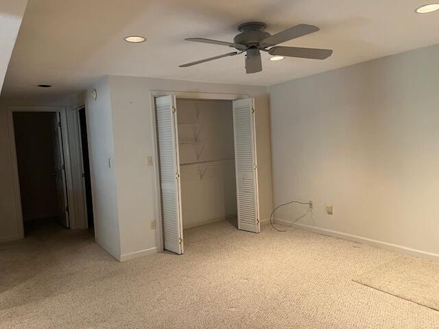 unfurnished bedroom featuring ceiling fan, light colored carpet, and a closet