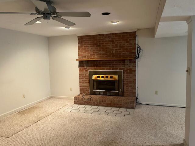 unfurnished living room featuring a brick fireplace, carpet flooring, and ceiling fan