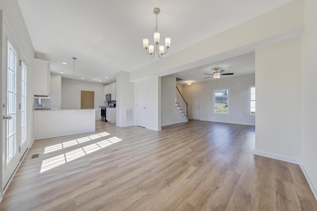 unfurnished living room with light wood-style flooring, visible vents, stairway, a notable chandelier, and baseboards