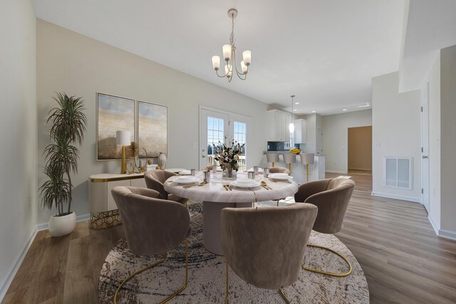 dining area featuring baseboards, wood finished floors, a notable chandelier, and visible vents