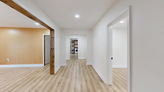 hallway with light wood-type flooring and washer / dryer