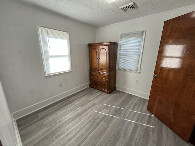 unfurnished bedroom with ornamental molding and light wood-type flooring