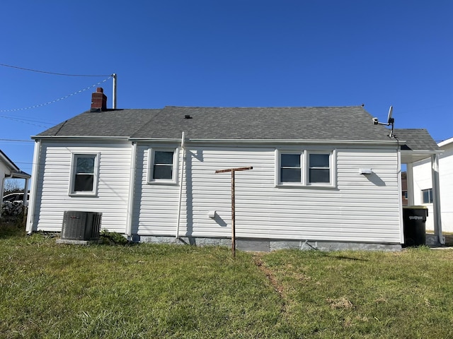 rear view of house with central air condition unit and a yard