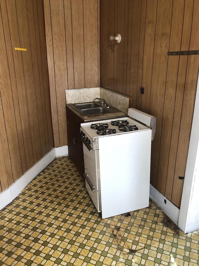 kitchen featuring sink, gas range gas stove, and wood walls