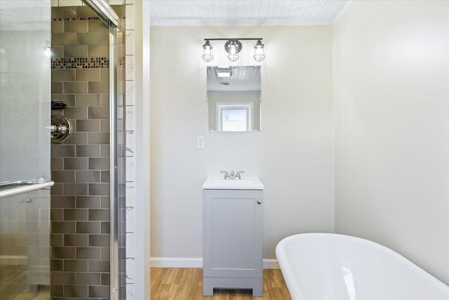 bathroom with vanity, wood finished floors, a soaking tub, a shower stall, and baseboards