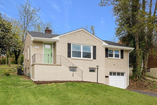 view of front of property with a front lawn, central AC, and a garage