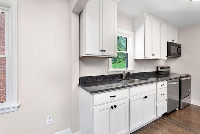 kitchen featuring appliances with stainless steel finishes, dark stone counters, white cabinets, sink, and dark hardwood / wood-style floors