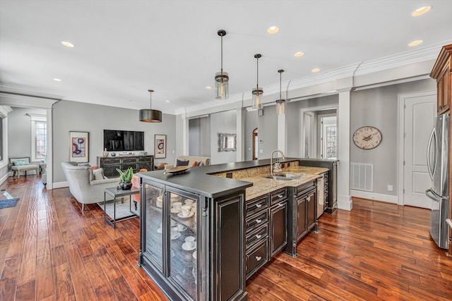 kitchen featuring visible vents, dark wood finished floors, a kitchen island with sink, freestanding refrigerator, and a sink