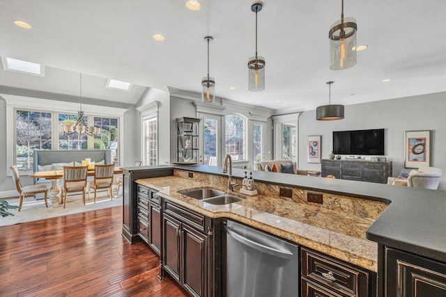 kitchen featuring a notable chandelier, a sink, stainless steel dishwasher, open floor plan, and a skylight