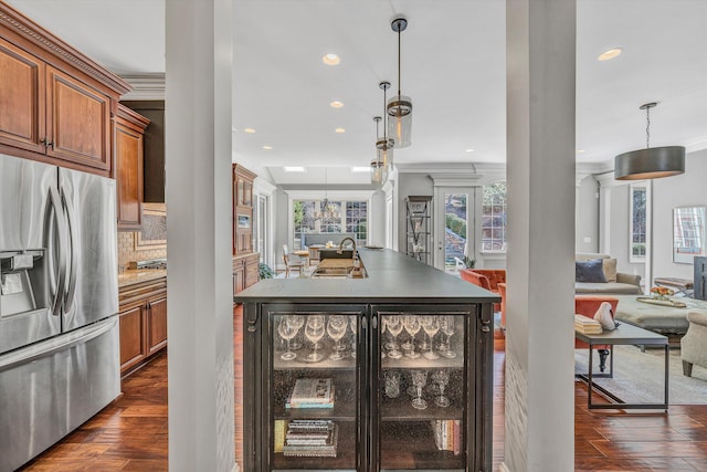 kitchen featuring open floor plan, brown cabinets, ornate columns, and stainless steel fridge with ice dispenser