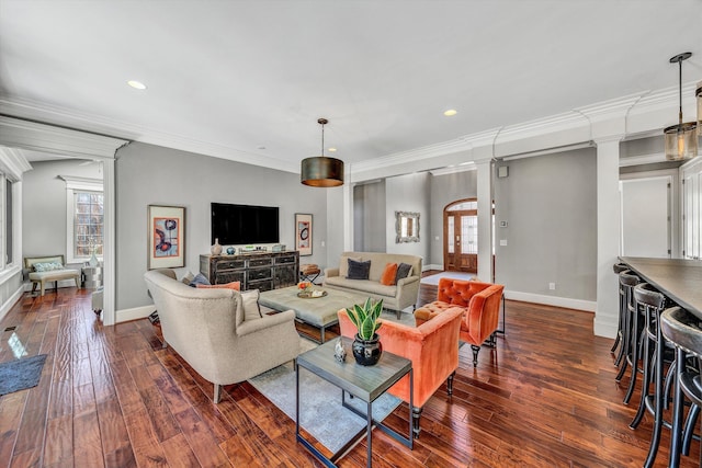 living room featuring dark wood finished floors, ornamental molding, baseboards, and decorative columns