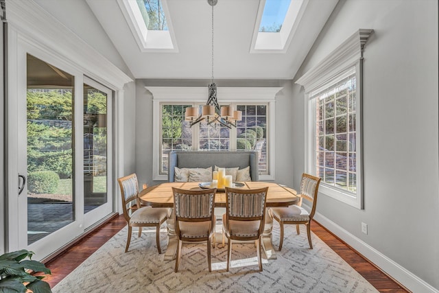 dining space featuring a wealth of natural light, a notable chandelier, and vaulted ceiling with skylight