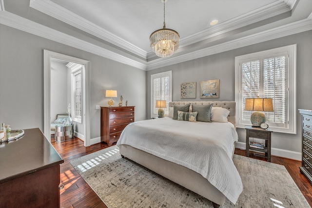 bedroom featuring a notable chandelier, a tray ceiling, dark wood finished floors, crown molding, and baseboards