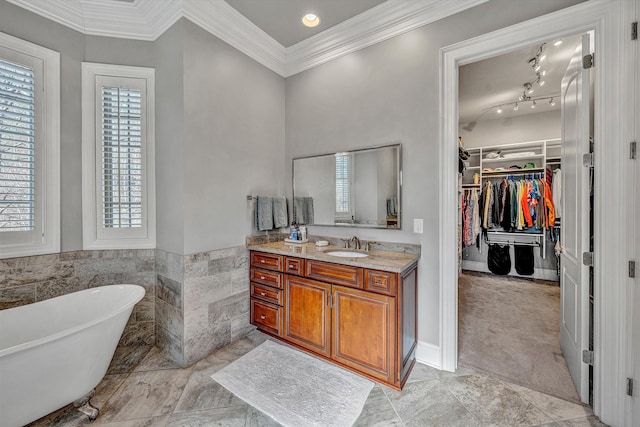 bathroom featuring vanity, ornamental molding, a freestanding bath, a spacious closet, and tile walls