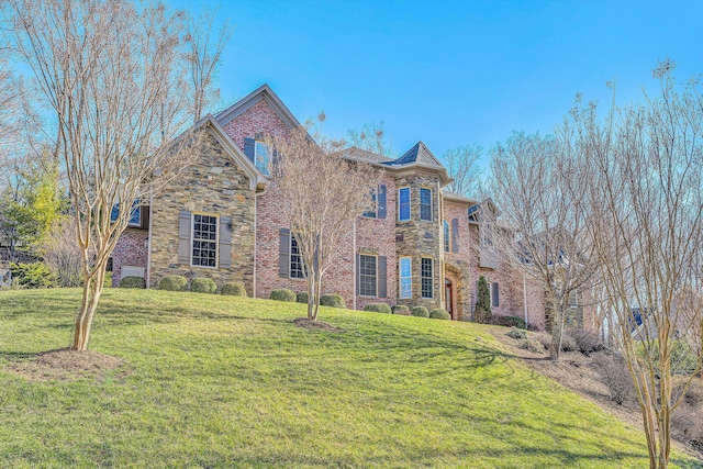 view of front of property with brick siding, stone siding, and a front yard