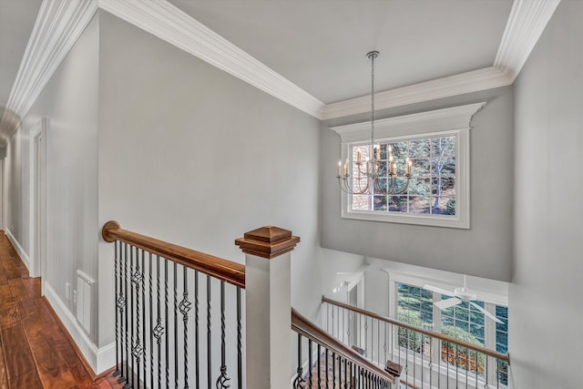 hallway featuring visible vents, an upstairs landing, a notable chandelier, ornamental molding, and wood finished floors