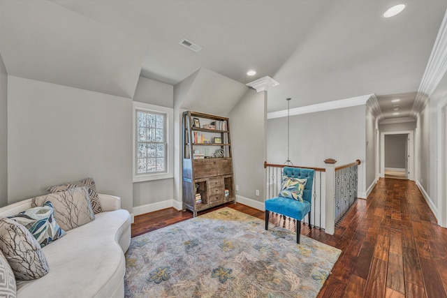 living area featuring baseboards, visible vents, vaulted ceiling, hardwood / wood-style flooring, and crown molding