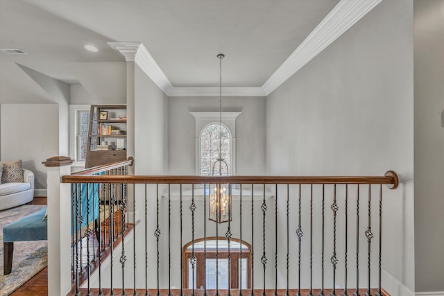 corridor featuring baseboards, wood finished floors, visible vents, and ornamental molding