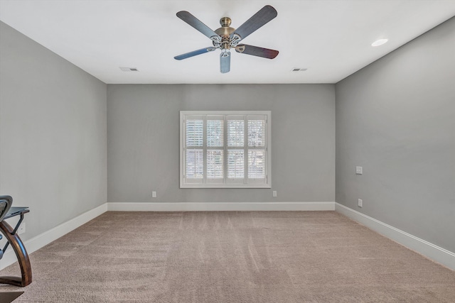 carpeted spare room featuring visible vents, baseboards, and a ceiling fan