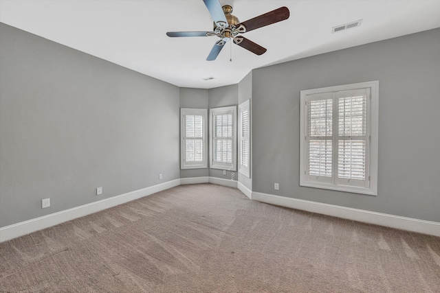 carpeted empty room with visible vents, baseboards, and a ceiling fan