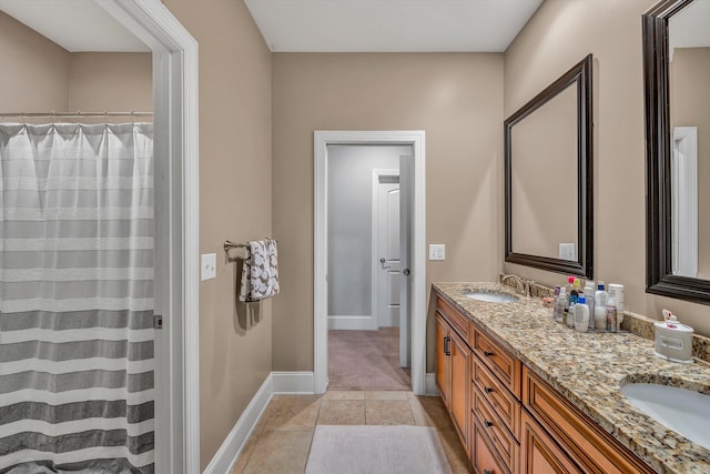 full bathroom featuring double vanity, a shower with curtain, baseboards, and a sink