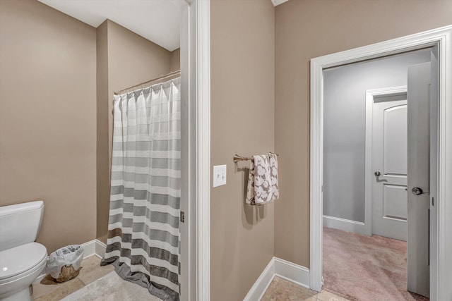 bathroom featuring a shower with shower curtain, baseboards, and toilet