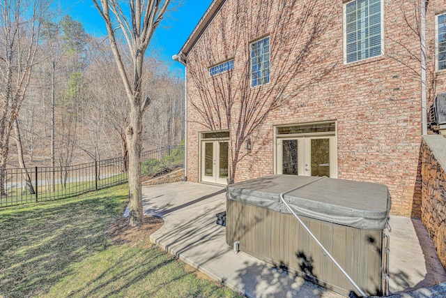 rear view of house with a hot tub, fence, french doors, a yard, and a patio area