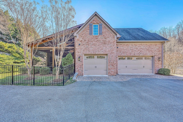 view of front of home featuring brick siding, fence, aphalt driveway, roof with shingles, and a garage