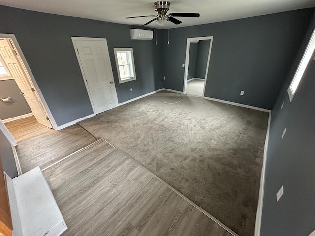 unfurnished bedroom with ceiling fan, a wall mounted AC, ensuite bathroom, and hardwood / wood-style floors