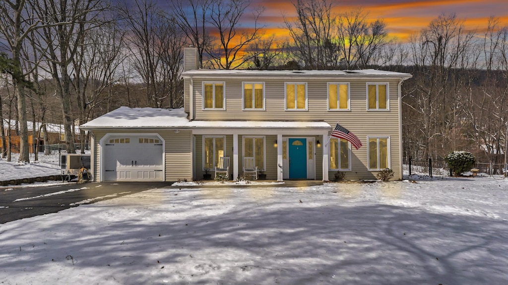 view of front of property featuring an attached garage, a chimney, and fence