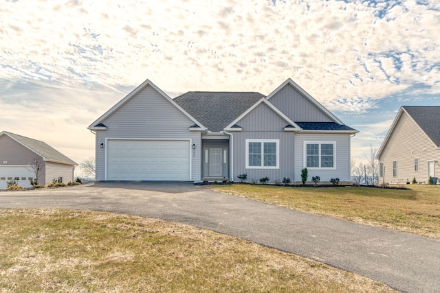 view of front of home featuring driveway, an attached garage, a shingled roof, a front lawn, and board and batten siding