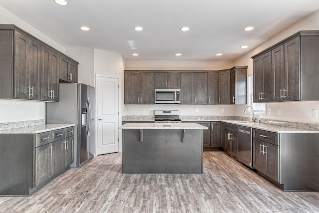 kitchen featuring light wood-style flooring, a sink, a kitchen island, stainless steel appliances, and dark brown cabinets