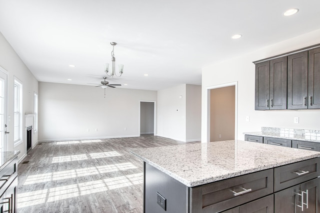 kitchen featuring a ceiling fan, light stone counters, recessed lighting, light wood-style floors, and dark brown cabinetry