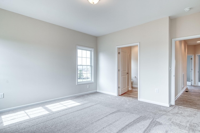 unfurnished bedroom featuring baseboards, carpet, and ensuite bath