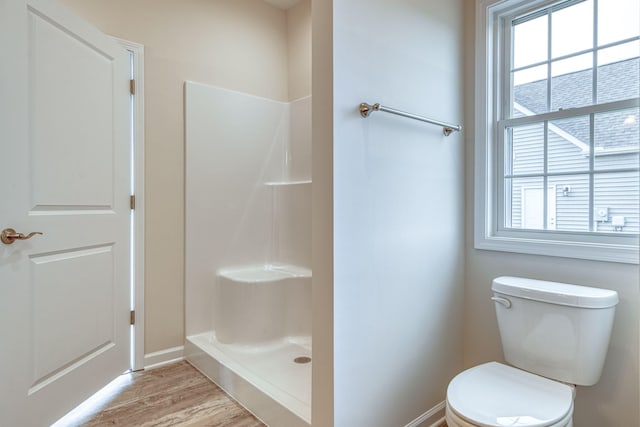 bathroom featuring baseboards, toilet, walk in shower, and wood finished floors