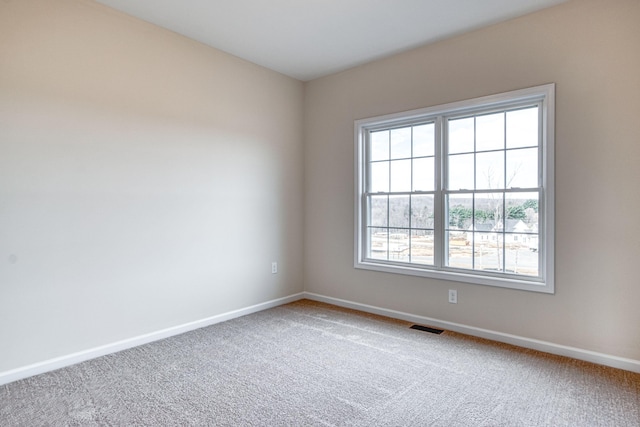 carpeted empty room featuring visible vents and baseboards