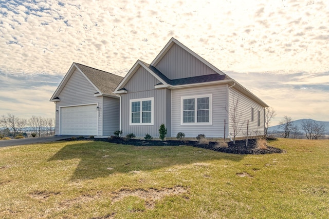 view of front facade featuring driveway, roof with shingles, an attached garage, a front lawn, and a mountain view