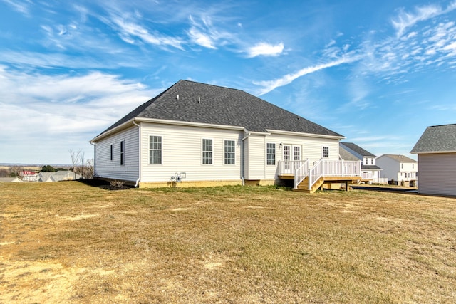 back of house featuring a shingled roof, a lawn, and a wooden deck