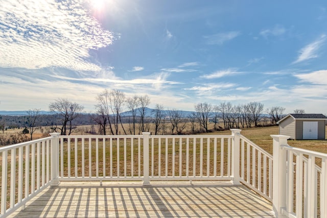 wooden deck with an outbuilding, a rural view, a mountain view, and a storage shed