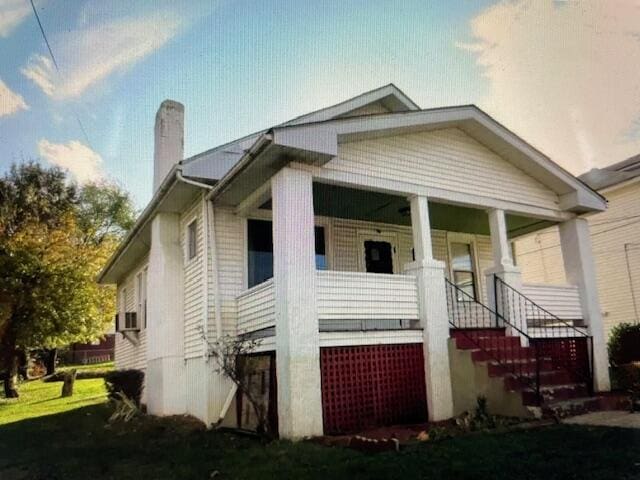 view of front of home featuring stairway, a porch, and a chimney