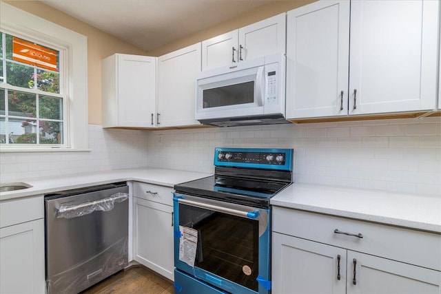 kitchen featuring dark wood-style floors, white cabinetry, appliances with stainless steel finishes, and decorative backsplash